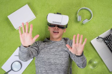 Sanal gerçeklik gözlük yeşil yerde yatarken giyen Asya adam üstten görünüm.