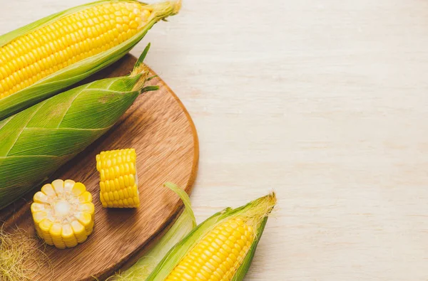 Sweet corns. Fresh corn cobs on wooden board  on table with copy space