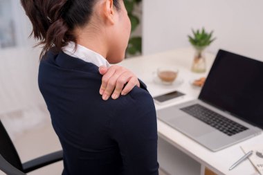 Boyun ağrısı ile genç iş kişi. Tablo arka plan üstünde laptop ile boyun el ele.