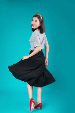 Gülümseyen Asyalı kadın tam vücut pin-up tarzı elbise üzerinde mavi giyinmiş..