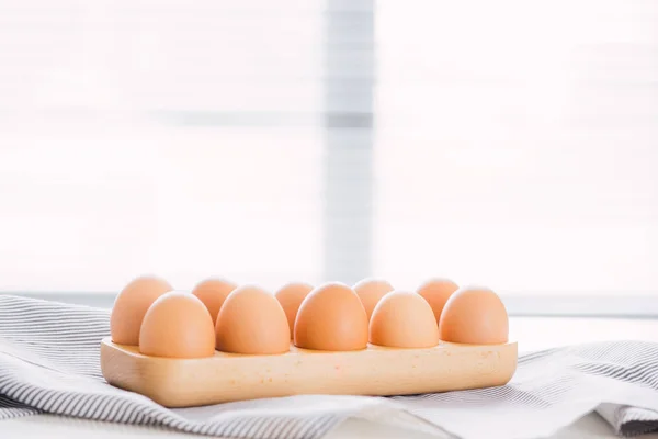 Eggs in wooden box with napkin on white kitchen table