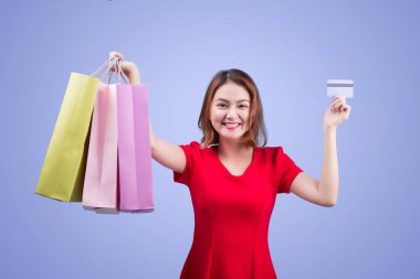 Asyalı kadın alışveriş torbaları ve kredi kartı karşı menekşe arka plan ayakta tutan