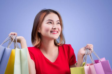 Menekşe arka plan üzerinde renkli alışveriş torbaları ile güzel Asyalı kadın 