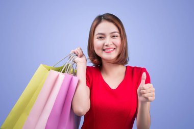 Renk alışveriş torbaları tutarak ve başparmak gösterilmesini güzel genç Asyalı kadın