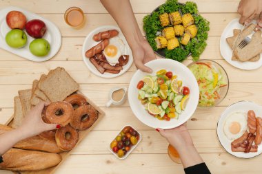 Arkadaşlarınızla akşam yemeği zevk. Grup birlikte ahşap masada oturmuş yemek yerken insan Üstten Görünüm