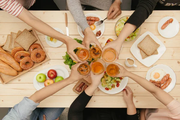 Enjoying dinner with friends. Top view of group of people having dinner together sitting at wooden table and holding glasses