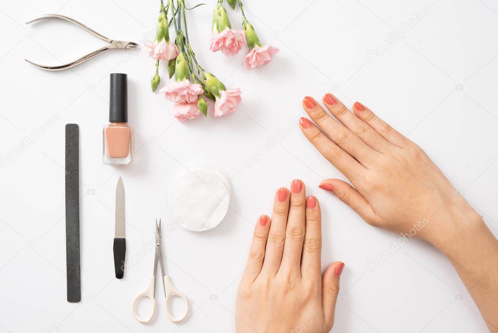 Female hands applying purple nail polish on wooden table with towel and nail set