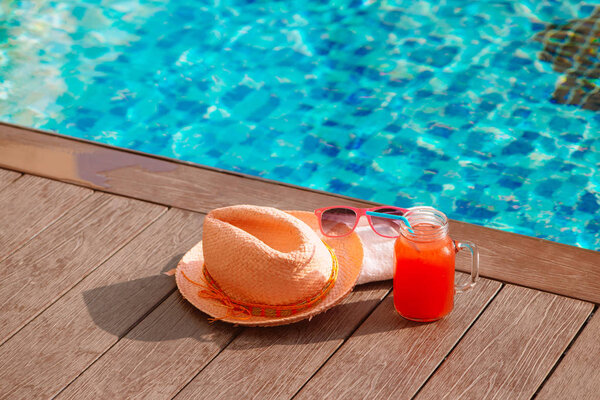 Арбузный коктейль из свежих фруктов с солнцезащитными очками и соломенной шляпой на границе бассейна - праздничная концепция
