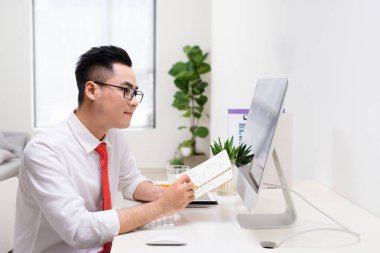 Mutlu işadamı ile kitap el bilgisayar monitörü Office bakarak
