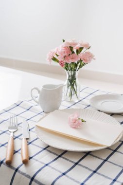 Tablo ayarı yemekleri, çatal bıçak takımı ve beyaz arka plan üzerinde çiçekler
