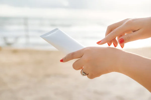 青い空を背景 Spf の日焼け止め保護と肌ケアの概念の海とビーチで日焼け止めを持つ女性の手 — ストック写真