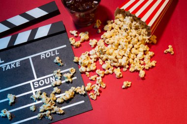 Sinema kavramı. Klaket, Bilet ve kırmızı bir arka plan üzerinde patlamış mısır