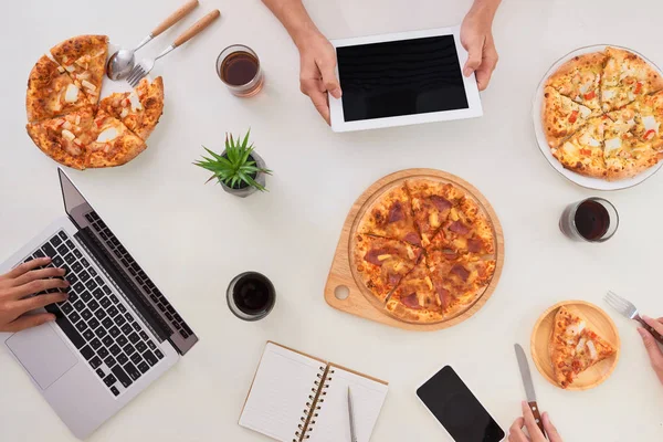 The office staff eat pizza and drink coffee in the business office. They have a break in their work. They are resting.