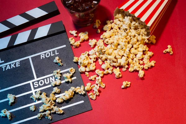 Sinema kavramı. Klaket, Bilet ve kırmızı bir arka plan üzerinde patlamış mısır