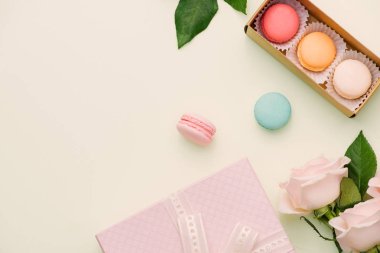 Renkli macaroons ve gül hediye kutusu üzerinde açık yeşil çiçeklerle. Tatlı macarons hediye kutusunda. Üstten görünüm