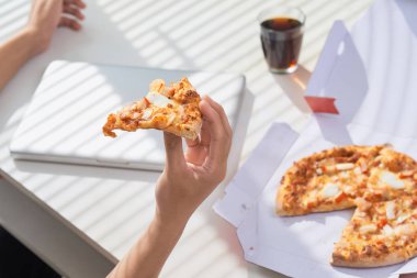 Pizza yiyip bir dizüstü bilgisayar ile sosyal ağ.