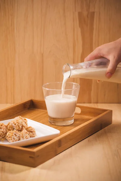 milk pour from bottle, almond candies on wooden background