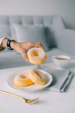 Yemek ve ekmek, şeker Toppings ile lezzetli taze ve tatlı çörek üzerinde beyaz çanak tutan el.