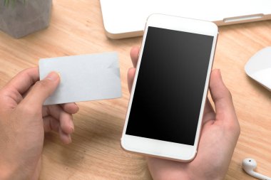 Portre fotoğraf, el kredi kartı tutan ve smartphone kullanarak iş adamı. Online ödeme plastik kart. Yatay mockup. Bulanık, film etkisi