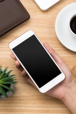 Üstten görünüm insan olarak masanın üzerinde boş bir ekran cep telefonu kullanarak.