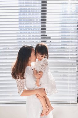 Oturma odasında dalga anne ve bebek kız. Kızı tutan Laughing.Mother.