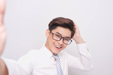 Kamera tutarak ve beyaz duvar arka plan üzerinde izole selfie yapma yakışıklı delikanlı