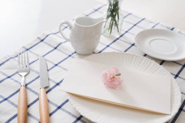 Tablo ayarı yemekleri, çatal bıçak takımı ve beyaz arka plan üzerinde çiçekler