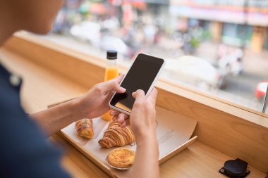 Erkek suyu ve tatlı tatlı ile Teras kafede oturur iken akıllı telefonu üzerinden internet sitesinde gerekli bilgi arar