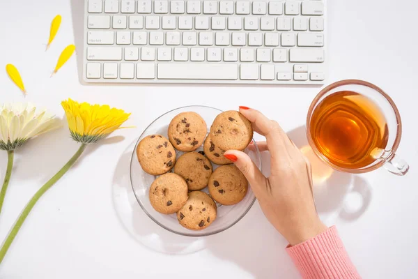 workspace with notebook keyboard, flowers and tea cup on white background. Flat lay, top view office table desk.