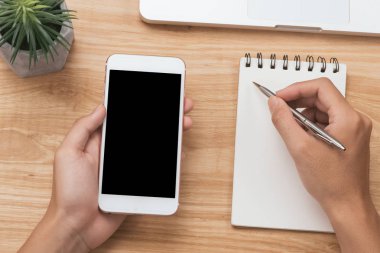 Genel gider yazarken akıllı telefon fotoğraf makinesi ve kahve masasında not etmek üstünde tutan işadamı el görünümünü