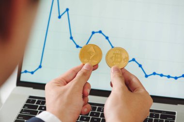 Fiziksel bitcoins ve ethereum paraları grafik arka plan üzerinde onun elinde tutan adam