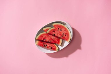 Pembe bir arka plan üzerinde beyaz tabak taze dilimlenmiş karpuz.