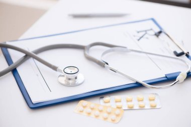 Stetoskop, reçete Pano ve kopya alanı ile beyaz arka plan üzerinde ilaç şişesi. Sağlık ve tıp kavramı.