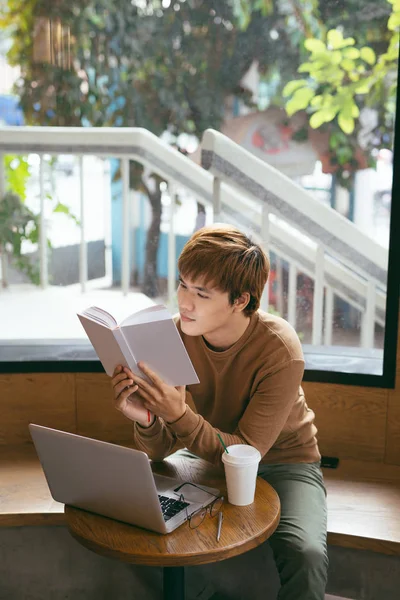 Pensivo Jovem Asiático Empresário Leitura Livro Desktop Com Laptop Xícara — Fotografia de Stock