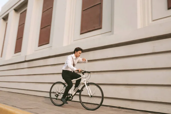 Hurry Asian businessman riding bike in rush hour.  Young man late for train work, meeting. Office life and business competition.