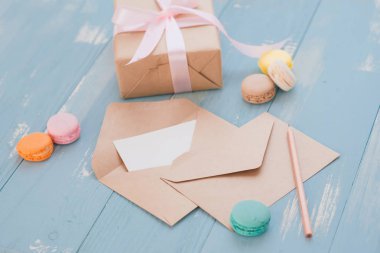 Hediye kutusu ve renk macaroons mavi ahşap arka plan üzerinde boş kağıt. Üstten görünüm. Düz yatıyordu.