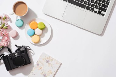 Rahat sabah kahvaltı pastel renkli macaroons, kahve fincanı, çiçek, dizüstü bilgisayar, kamera ve dizüstü