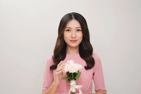 一个满意的年轻女子的肖像 身着粉红色的礼服持有玫瑰花花束隔离在白色背景 — 图库照片