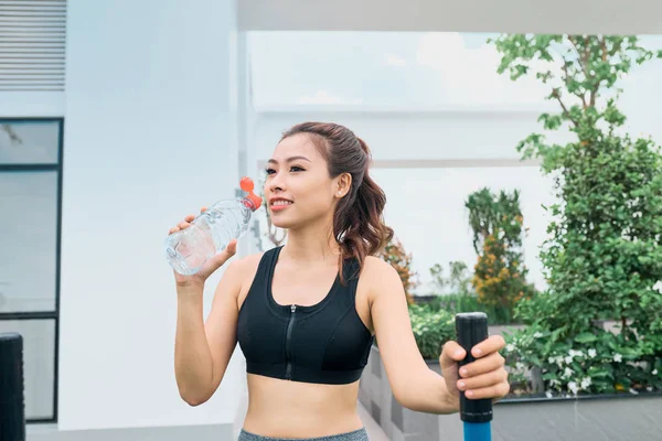 Dışarıda elinde su şişesiyle duran güzel bir bayan koşucunun fotoğrafı. Spor yaptıktan sonra spor yapan kadın..