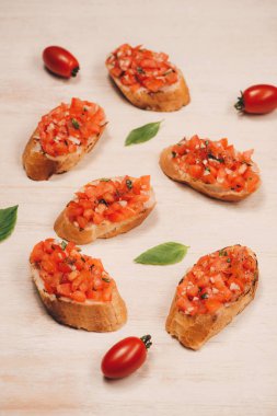 Közlenmiş domates, mozzarella peyniri ve bir kağıt üzerinde otlar ile İtalyan bruschetta