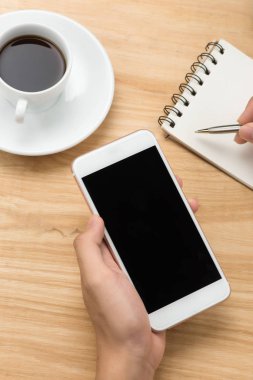 Akıllı telefon ve beyaz boş boş ekran kalemiyle beyaz Resepsiyon masasında tutan adam el. İş kavramı.