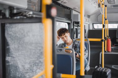 Otobüste smartphone kullanarak bir mavi kot ceket yakışıklı genç adam