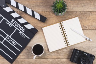 Film clapper kurulda, açık defter, kahve fincanı ve ahşap arka plan Kamerada film yönetmen resepsiyon. Üstten görünüm.
