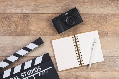 Film yönetmen resepsiyon ile film clapper kurulu ve ahşap arka plan üzerinde fotoğraf makinesi. Üstten görünüm.