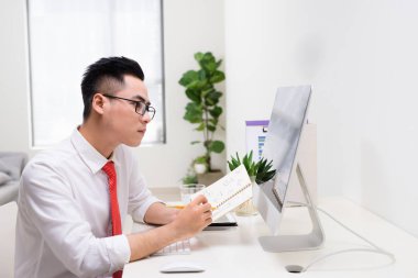 Mutlu işadamı ile kitap el bilgisayar monitörü Office bakarak