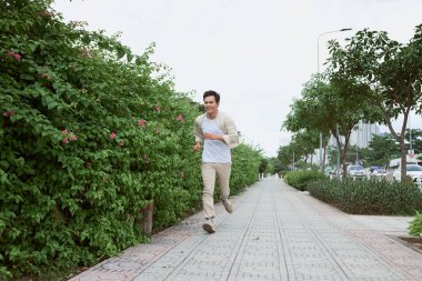 Yaz aylarında parkta koşan gülümseyen genç adam