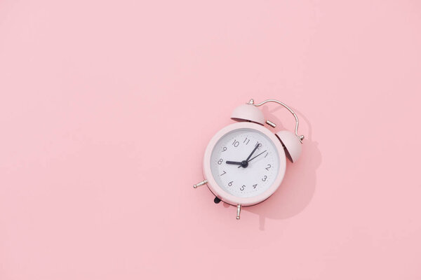 Light pink vintage alarm clock on pink background