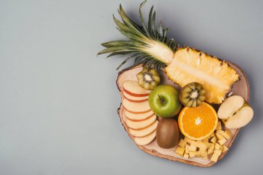 Plaka üzerinde çeşitli taze meyve. Elma, portakal, kivi, ananas, mandalina ahşap plaka üzerinde. Üstten görünüm
