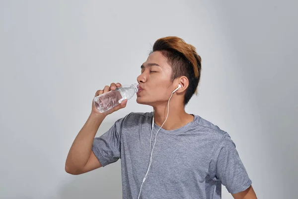 ハンサムな若い筋肉スポーツマン水のボトルを押しながら音楽を聴く — ストック写真