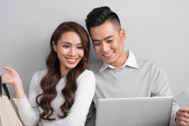 Alışveriş torbaları holding ve gri arka plan üzerinde izole laptop arıyorum bir çift